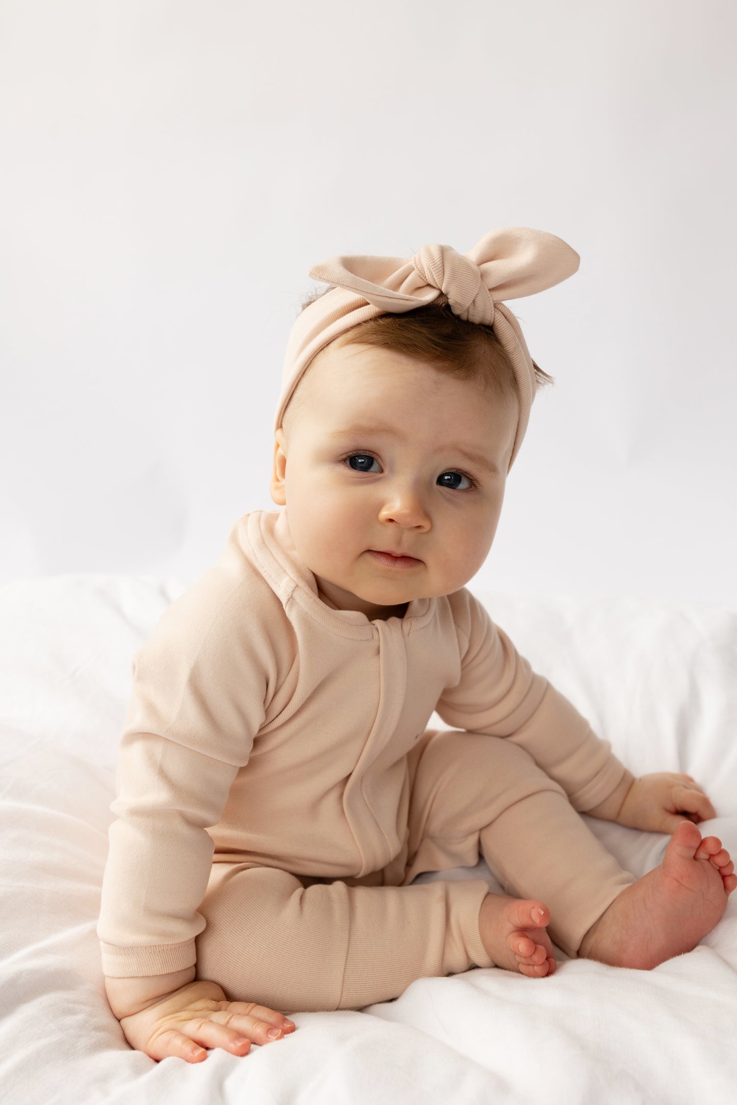Baby wearing a Apple Onesie in Baby Pink on a white background
