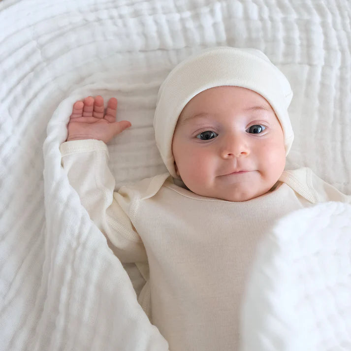 Baby wrapped in soft white organic muslin wrap from Fibre