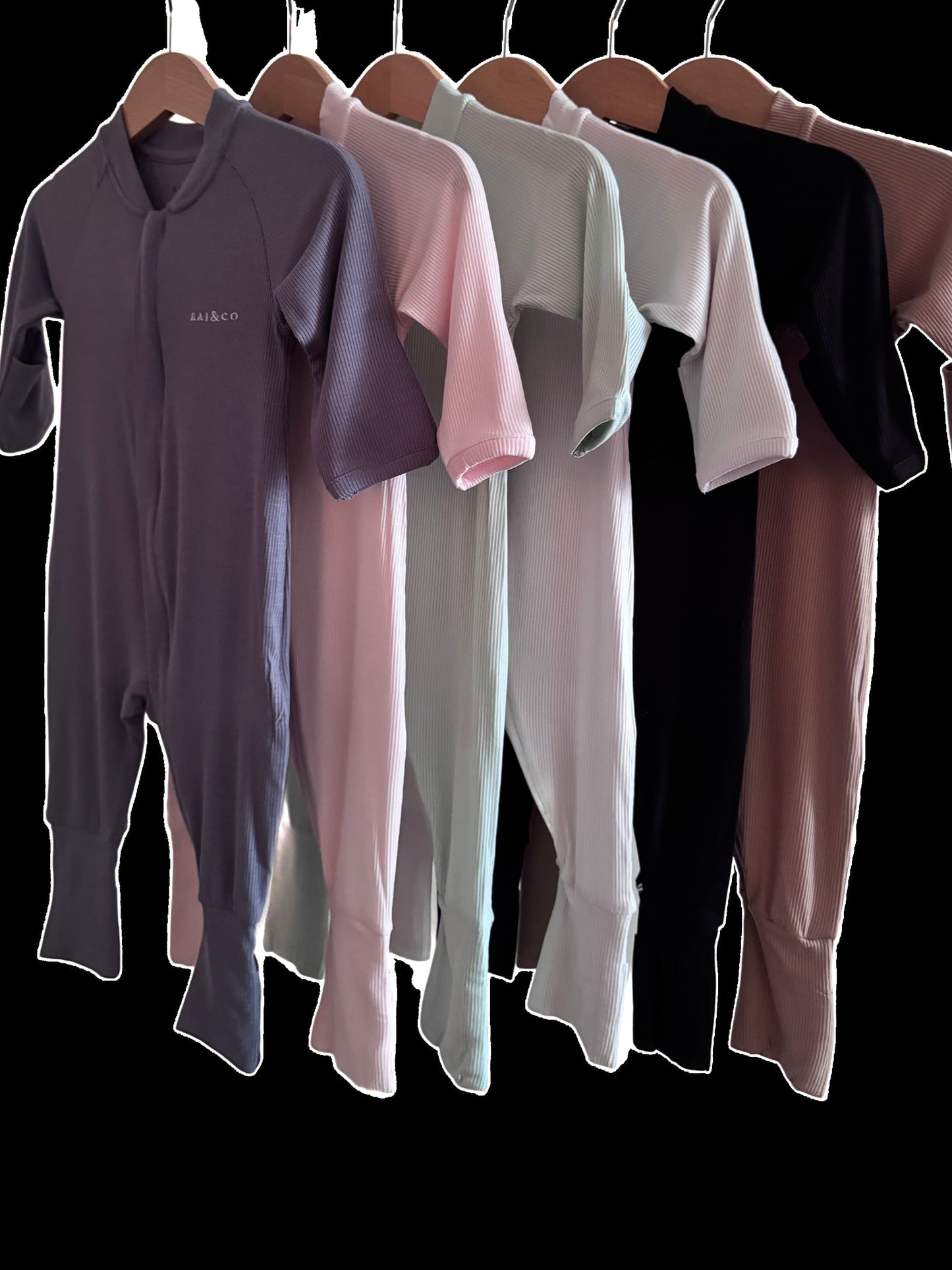 Set of Lightweight Eco Onesie in Available Colours hanging on a rack against a black background.