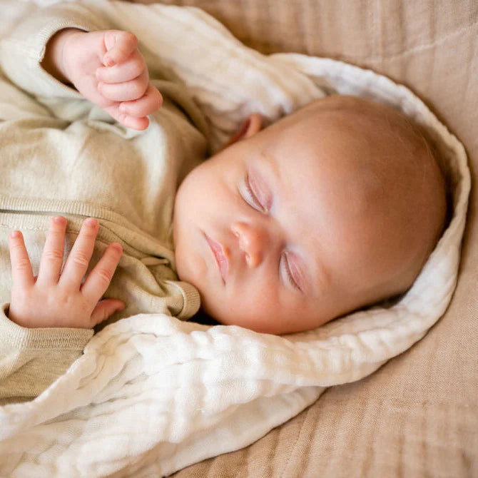 Baby sleeping in a white muslin wrap