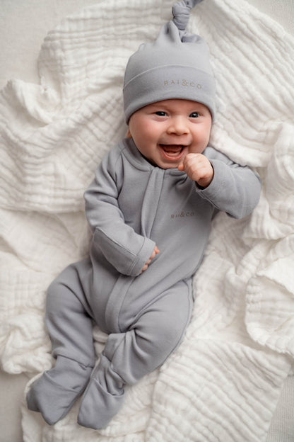 Baby lying on a white background, wearing the Baby Beanie Apple Knotted in Sky Blue.