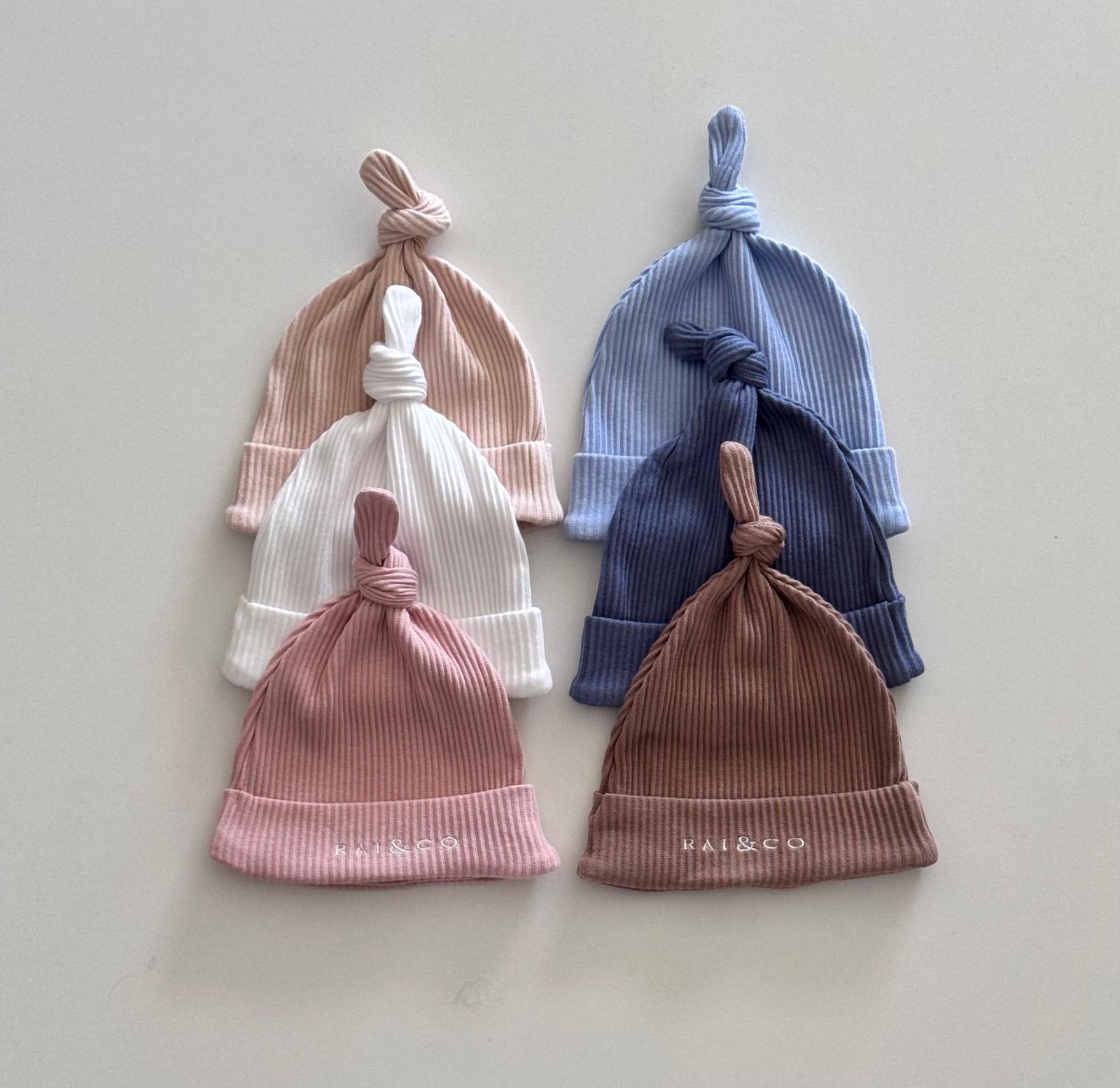 six Baby Beanie Ribbed Knotted  in available colours on a light background