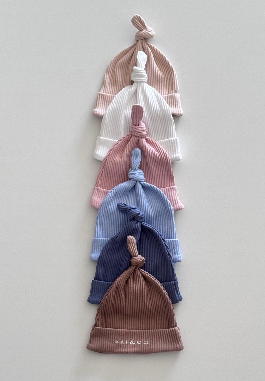 Stack of Baby Beanie Ribbed Knotted in Available Colour on a light gray background