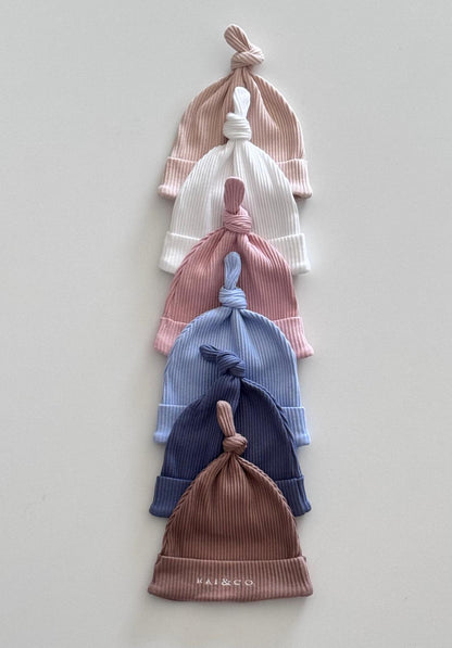 Stack of Baby Beanie Ribbed Knotted in Available Colour on a light gray background