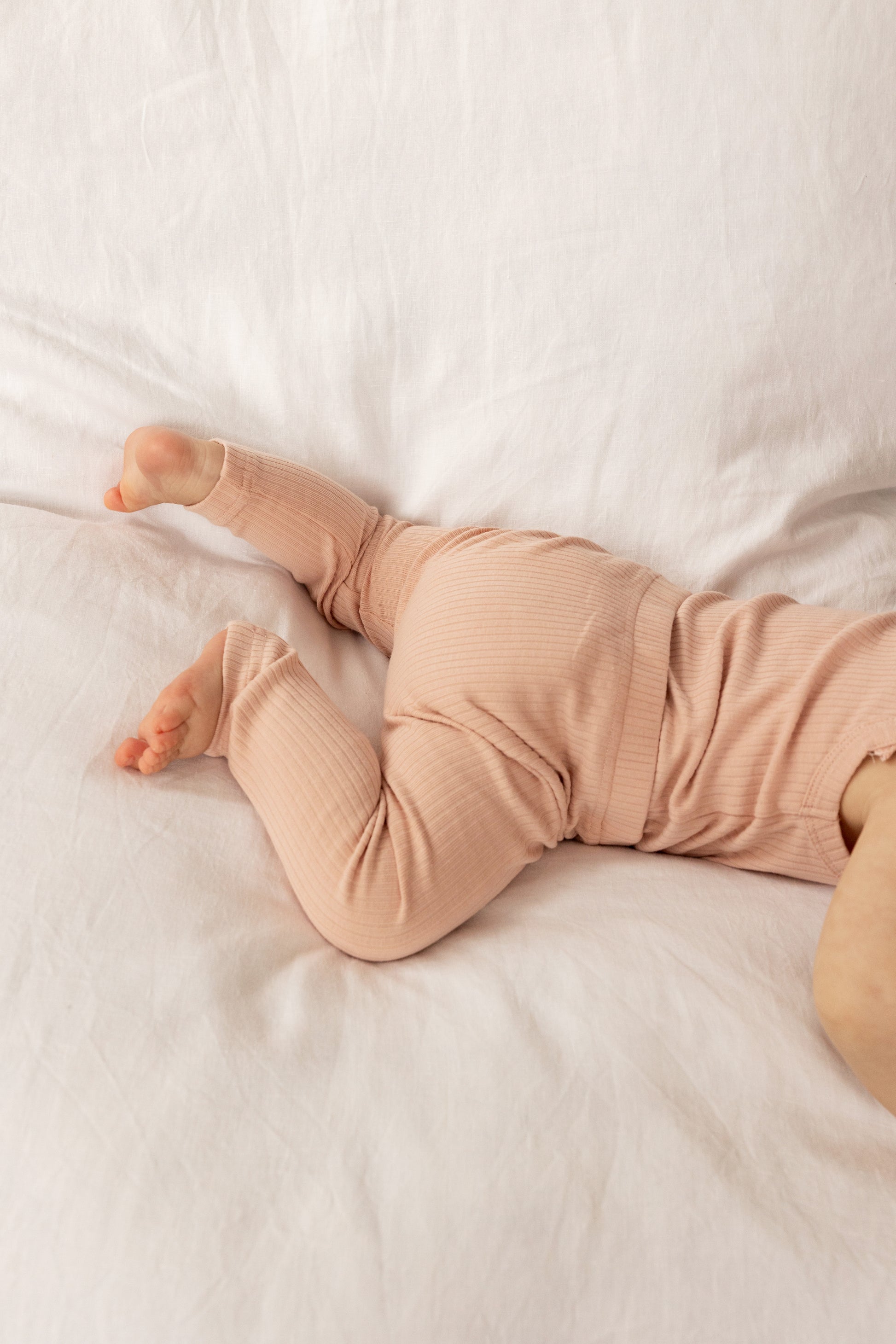 Baby wearing a Basic Leggings in Beige on a white bed 