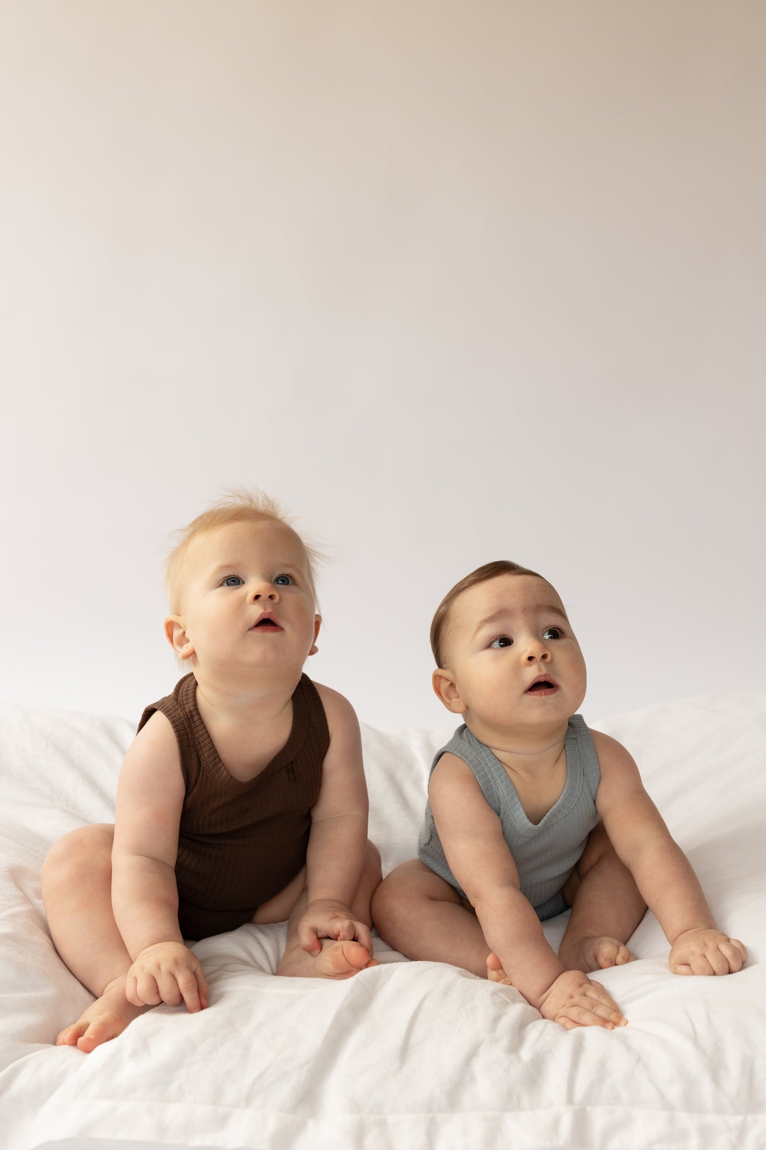two babies wearing a Basic Singlet Bodysuit in Dusty Blue and Chocolate 