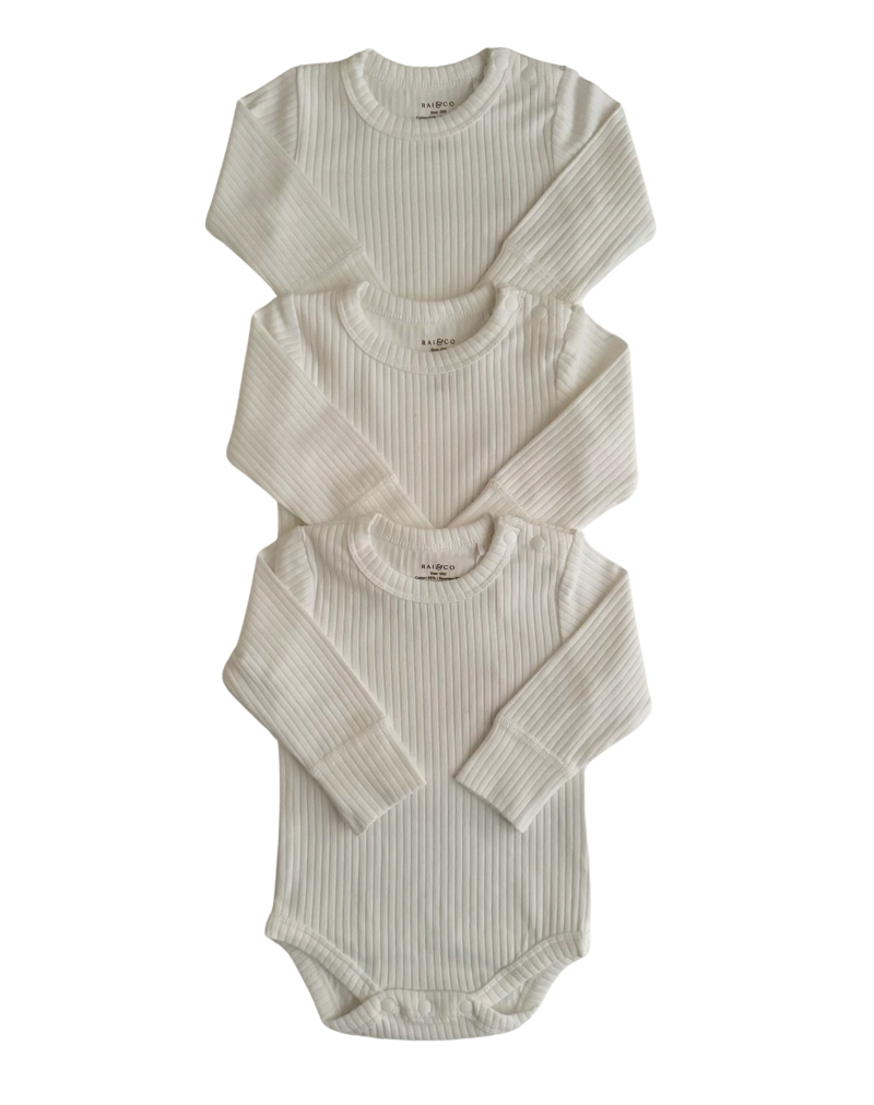 Three Basics Long Sleeve Bodysuits for babies, stacked on top of each other against a checkerboard transparency pattern. background.