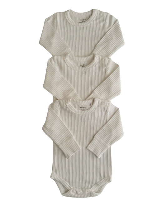 Three Basics Long Sleeve Bodysuits for babies, stacked on top of each other against a checkerboard transparency pattern. background.