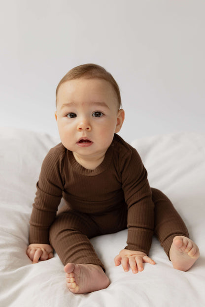 Baby wearing a Baby Boy Basic Longsleeve Bodysuit in Chocolate sitting on a white blanket 