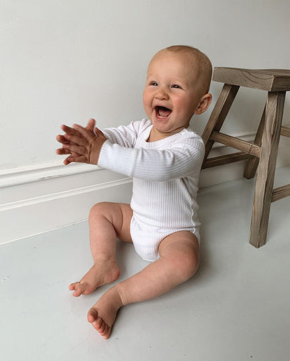 a baby wearing a Basics Long Sleeve Bodysuit in White