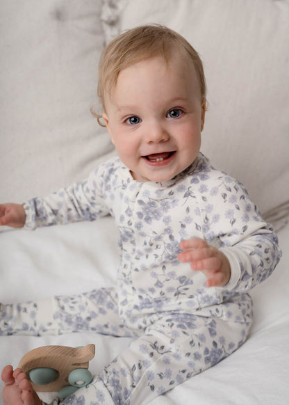 Baby wearing a Bloom Floral Onesie Blue sitting on a white surface