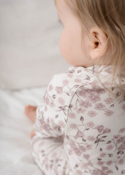 Baby wearing a Bloom Floral Onesie Pink on a light background