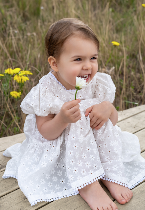 a young girl wearing a Eliza Embroidered Lace Dress in White 