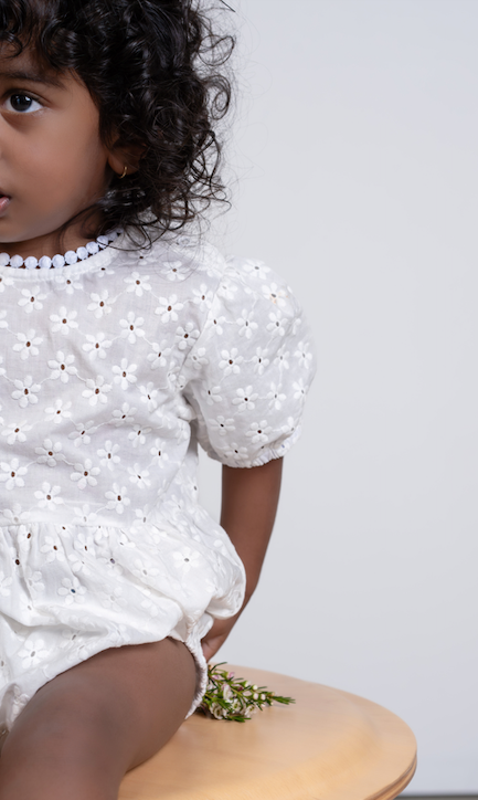a baby wearing a Eliza Embroidered Romper in White on a white background