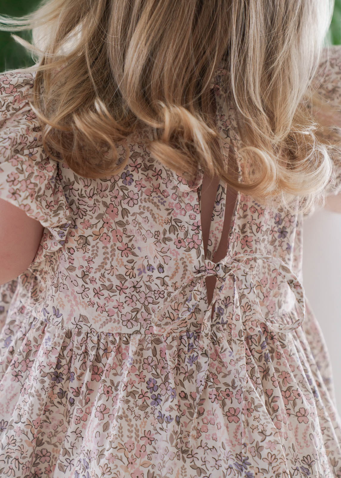 Close-up of Eliza Floral Dress in Cream with a blurred background