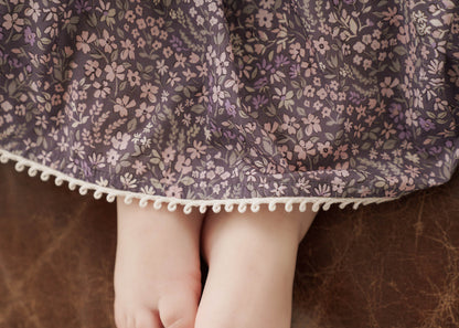 Close-up of a child wearing a Eliza Floral Dress in Indigo with a brown background