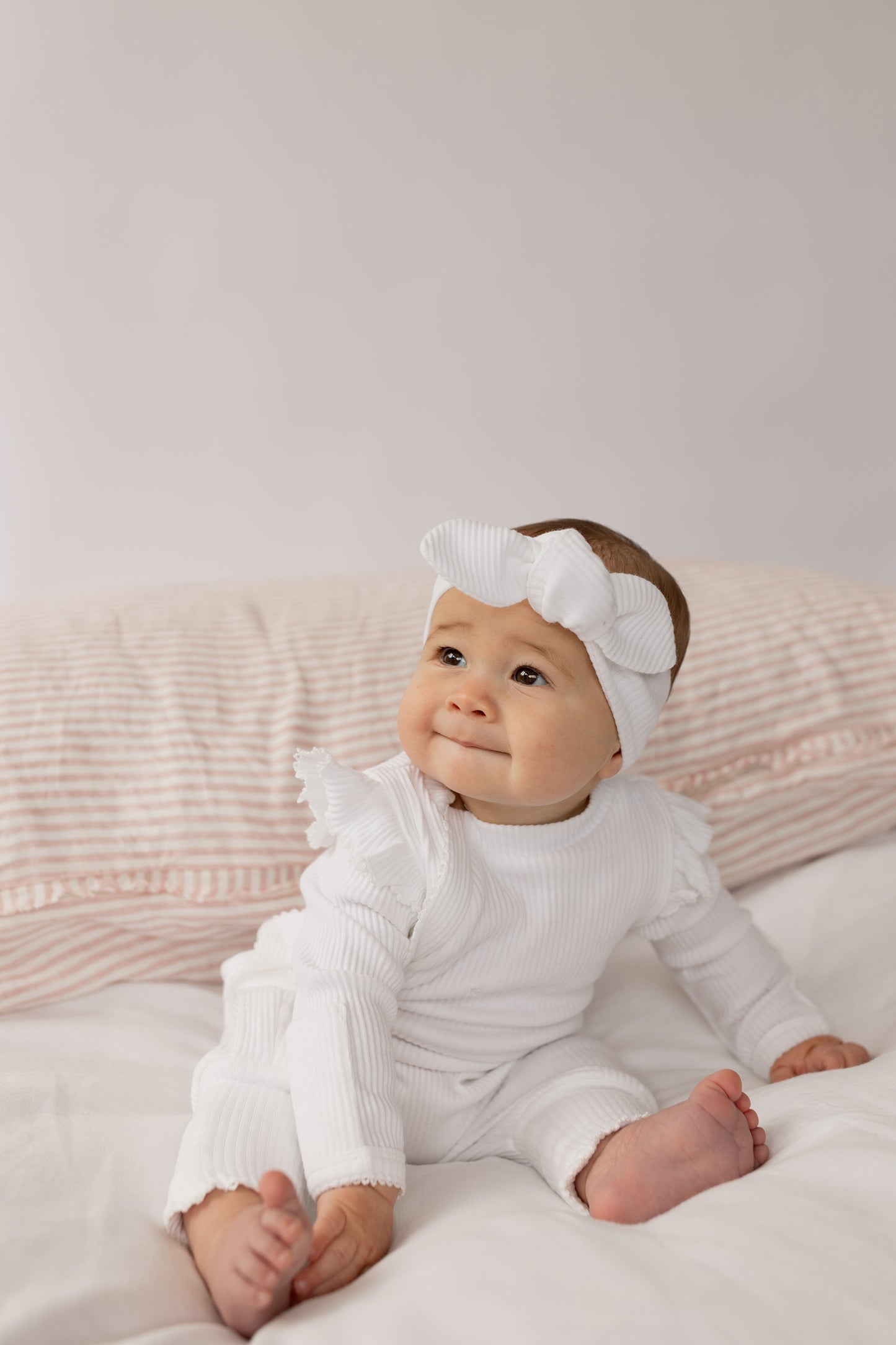 Baby wearing a Frill Ribbed Onesie in White 