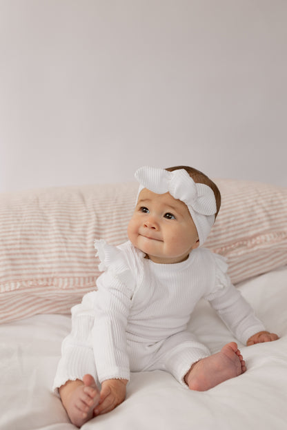 Baby wearing a Frill Ribbed Onesie in White 