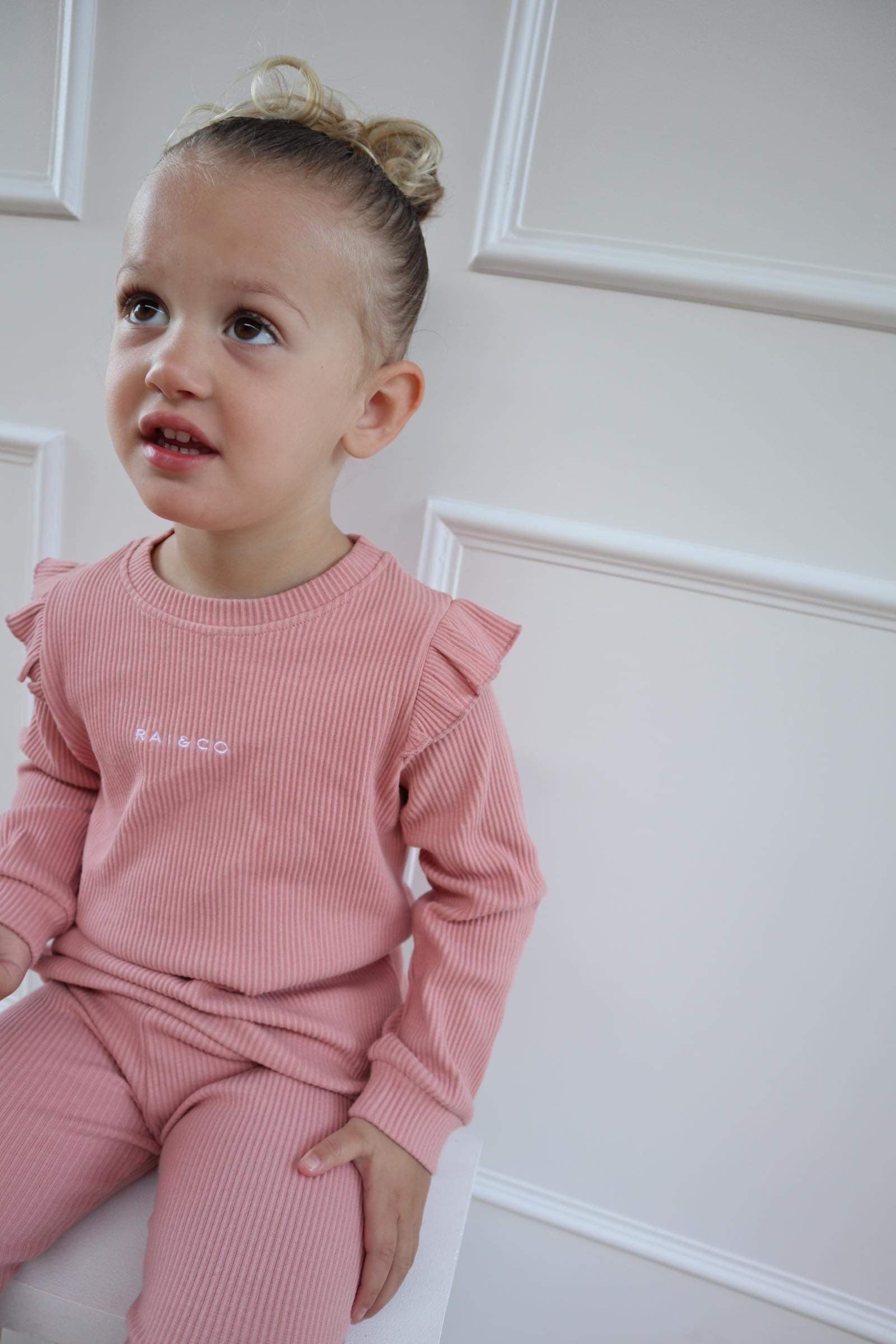 Child wearing a Frill Ribbed Two Piece in Light Pink  a white background