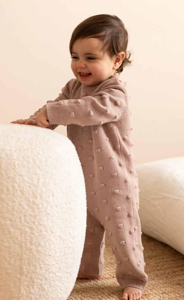 a baby wearing a Knitted Romper in Dusty Pink 