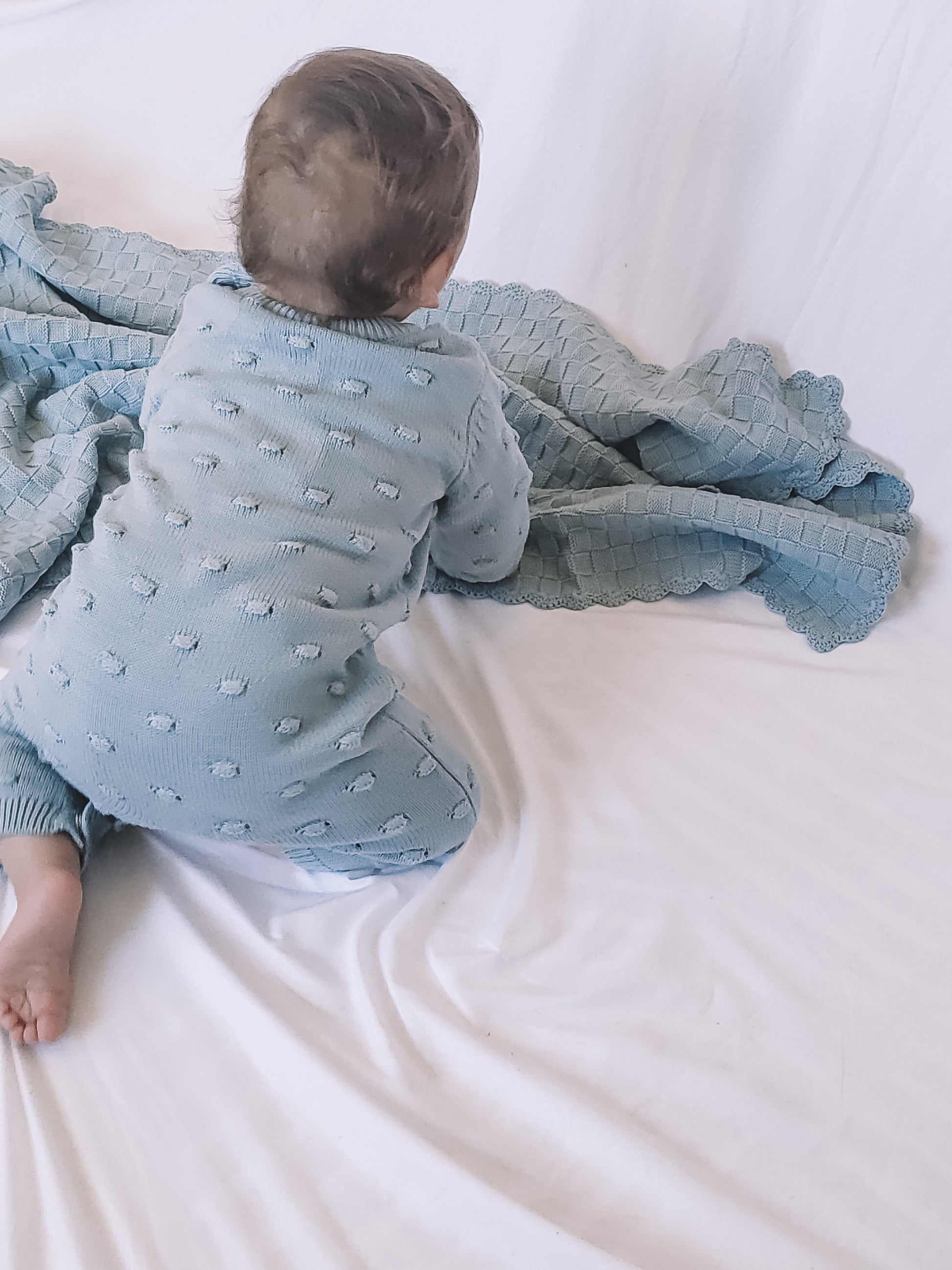 a baby wearing a Knitted Romper in Sky Blue on a white background 