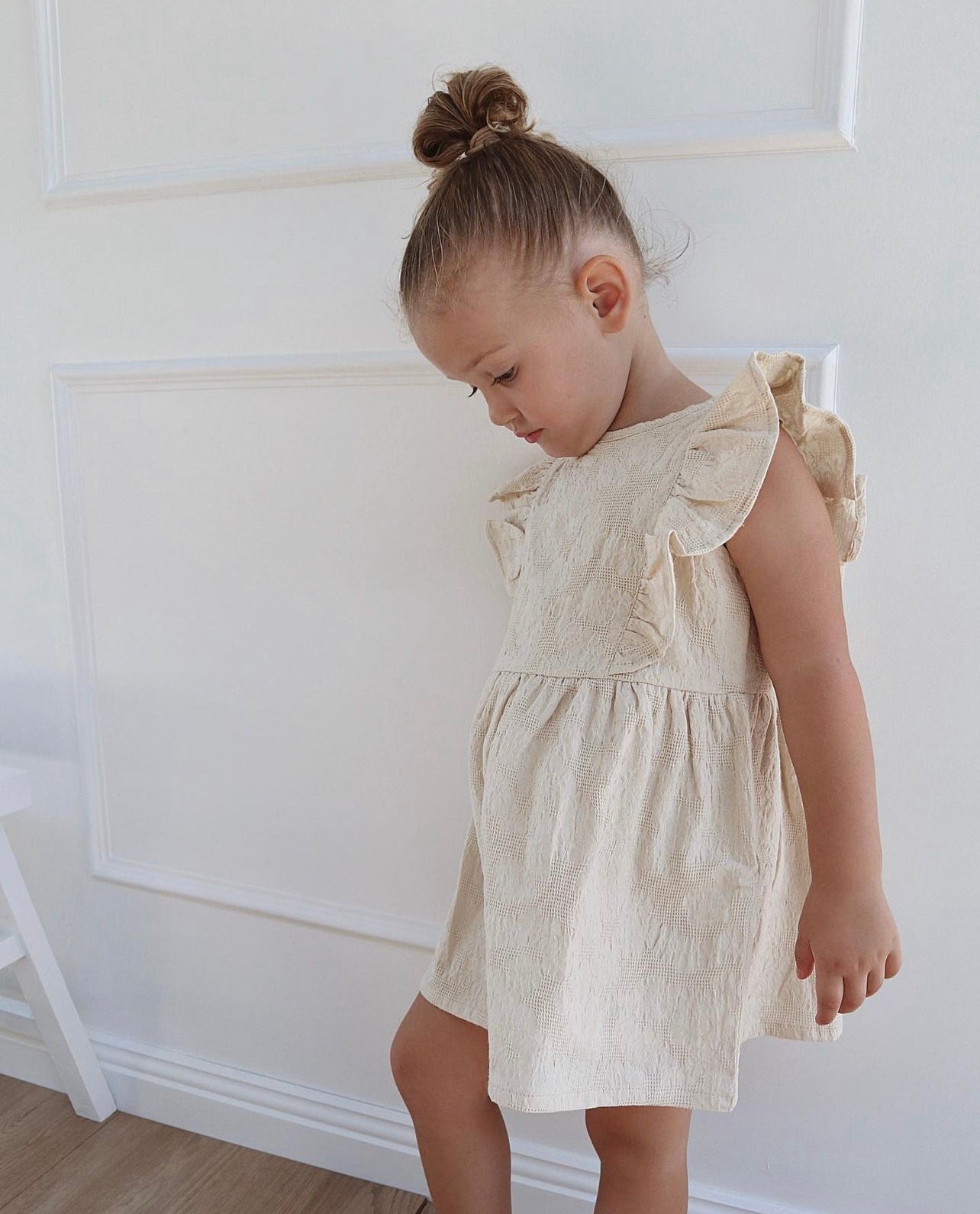 A young child wearing a Lou Lou Frilled Dress With Pilchers in Beige 