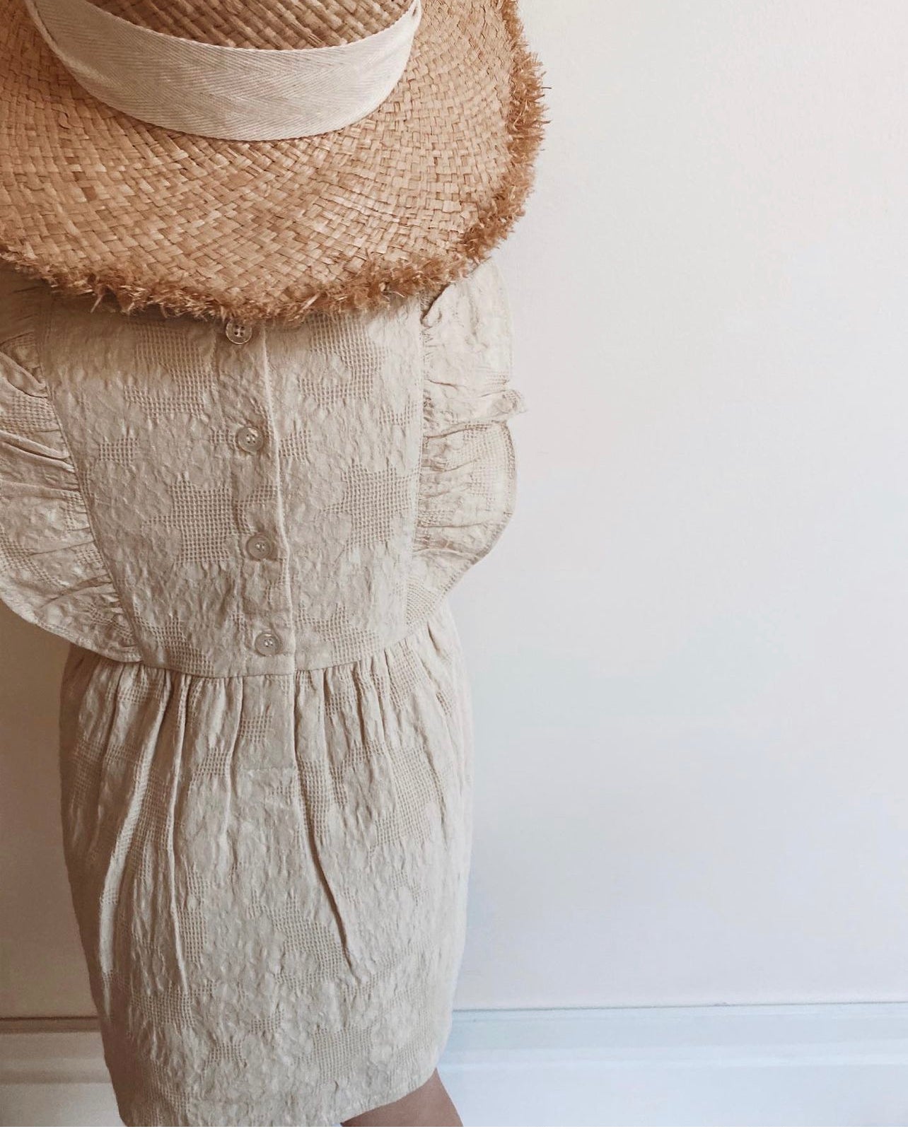 A young child wearing a Lou Lou Frilled Dress With Pilchers in Beige on a white background