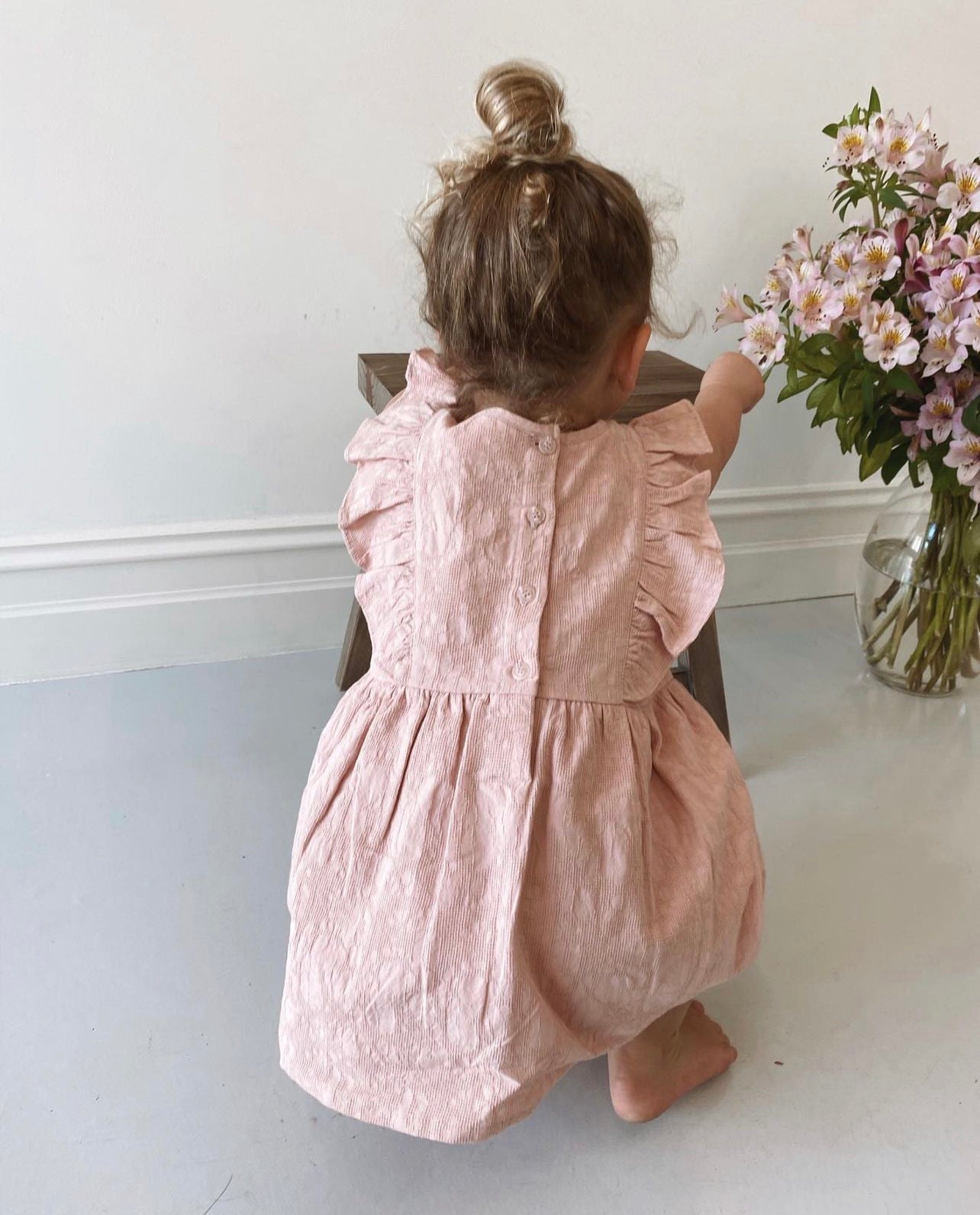 A young child wearing a Lou Lou Frilled Dress With Pilchers in Pink 