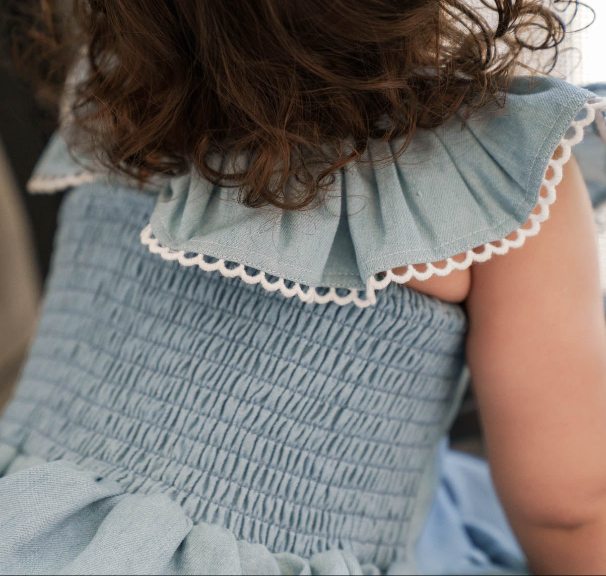 Close-up of a child wearing a Maddie Dress in Denim