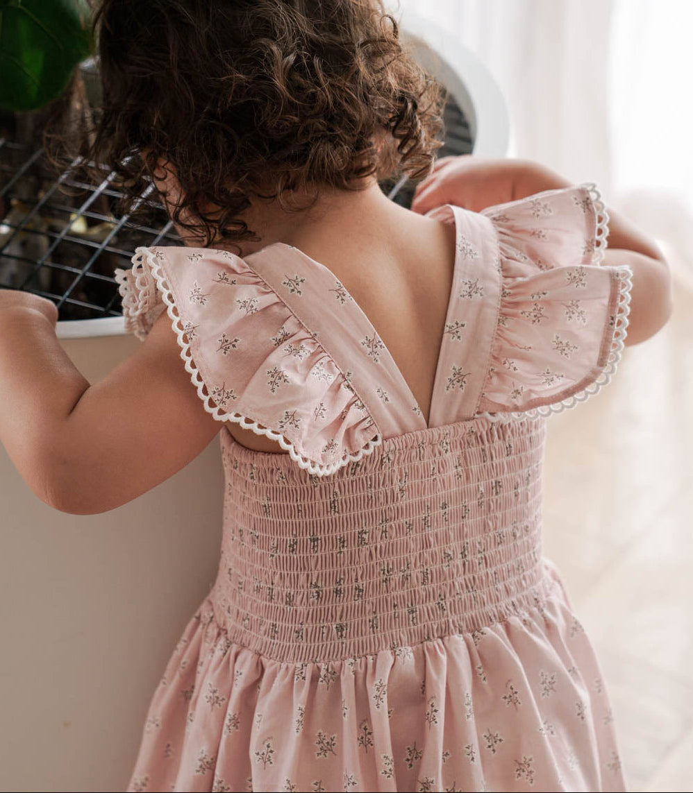 Child wearing a Maddie Dress in Pink Floral standing indoors.