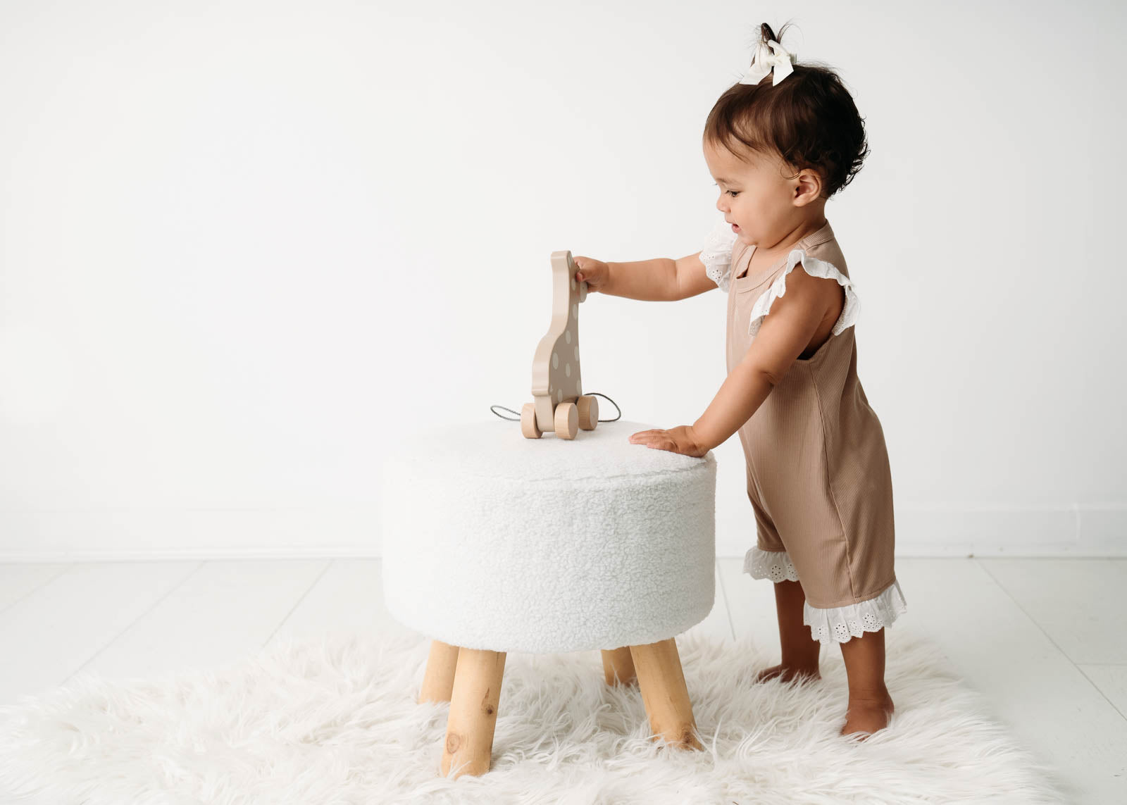 Baby wearing a Mini Ribbed Lace Frill Romper in Beige on a white background