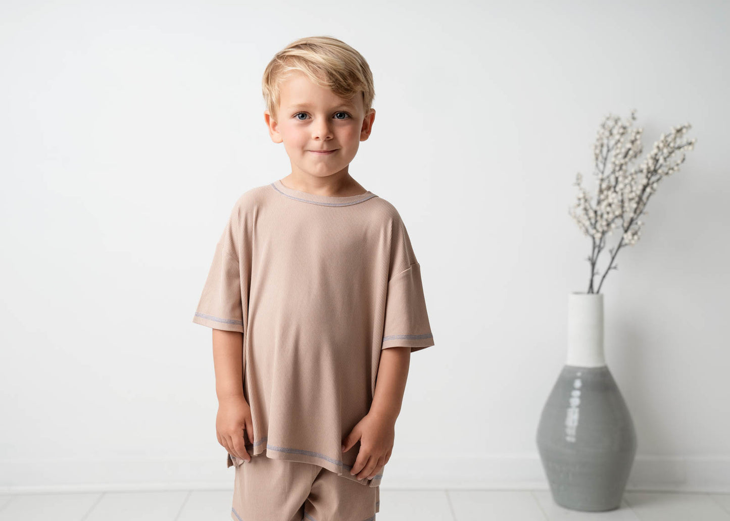A boy wearing a Mini Ribbed Oversized T-shirt in Beige on a white background