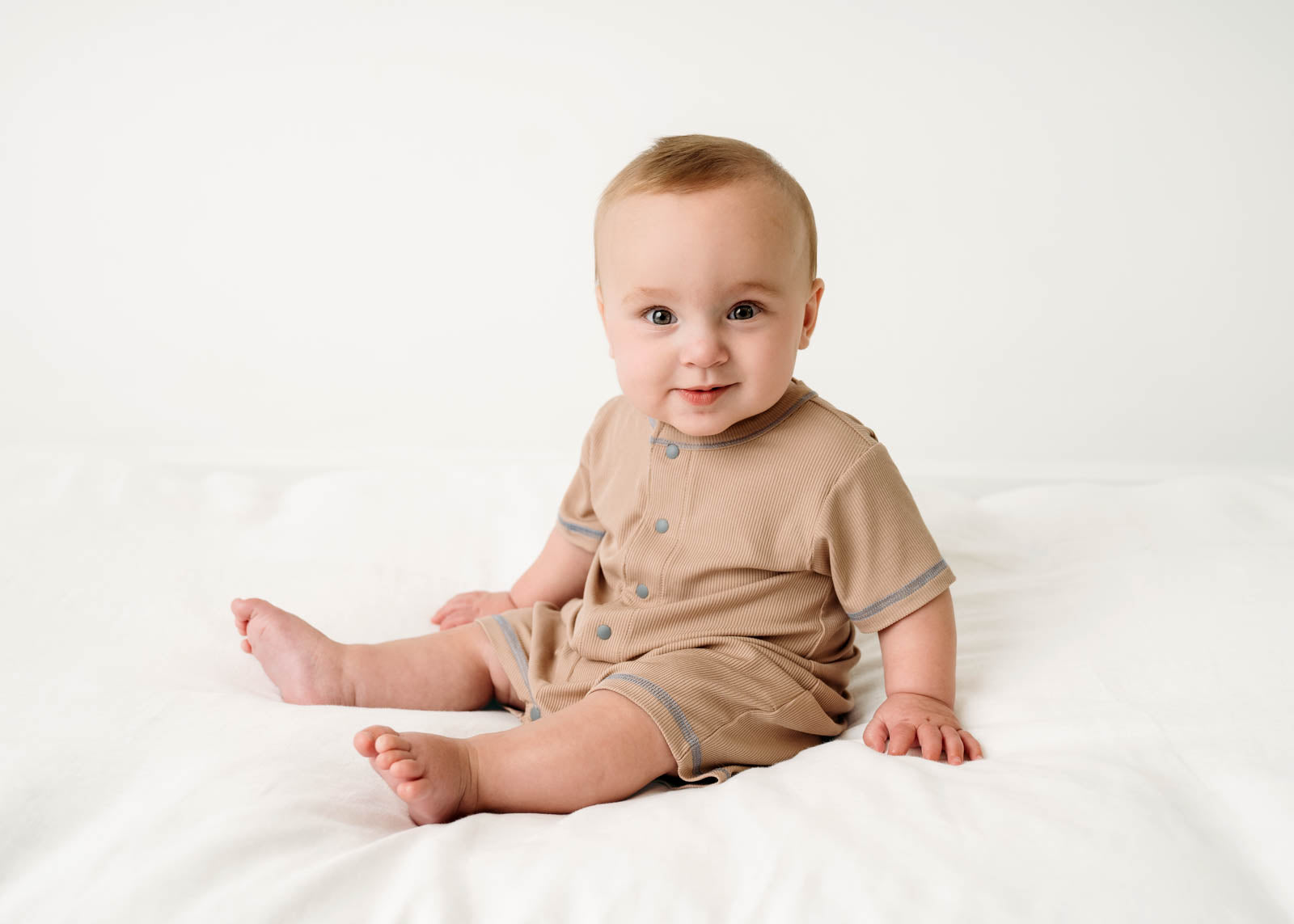 Baby wearing a Mini Ribbed Romper in Beige on a white background