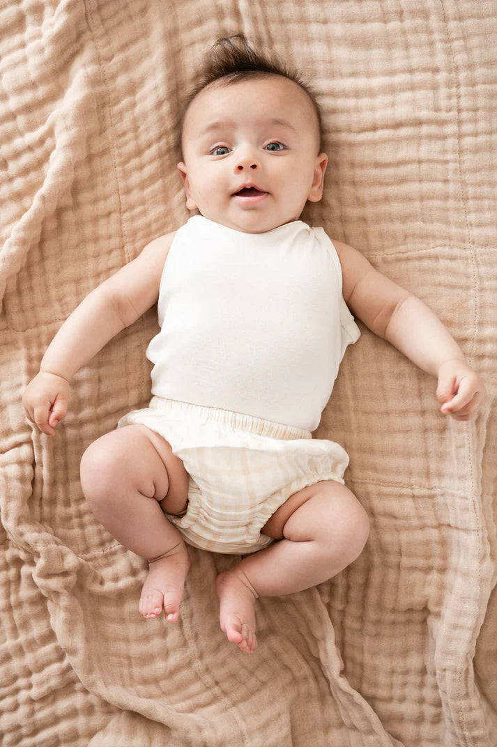 Baby lying down in Organic Undyed Cotton Muslin Wrap in Beige
