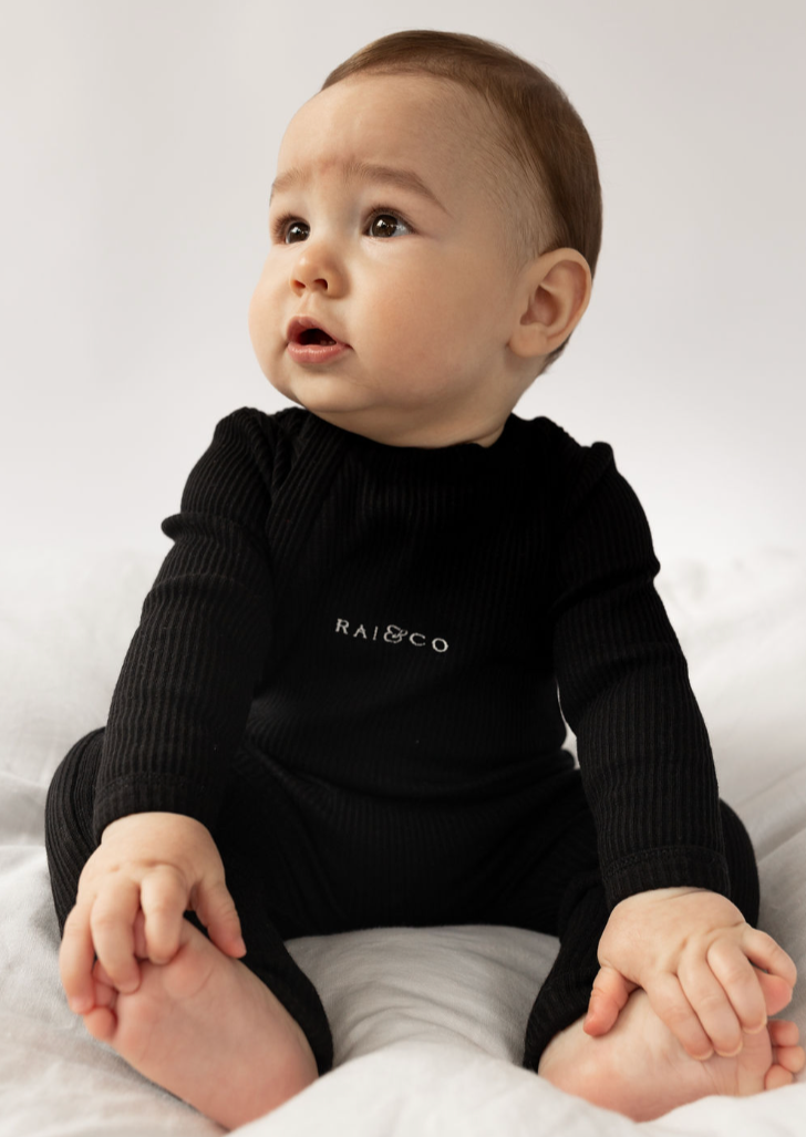 Baby wearing a Ribbed Onesie in Black  