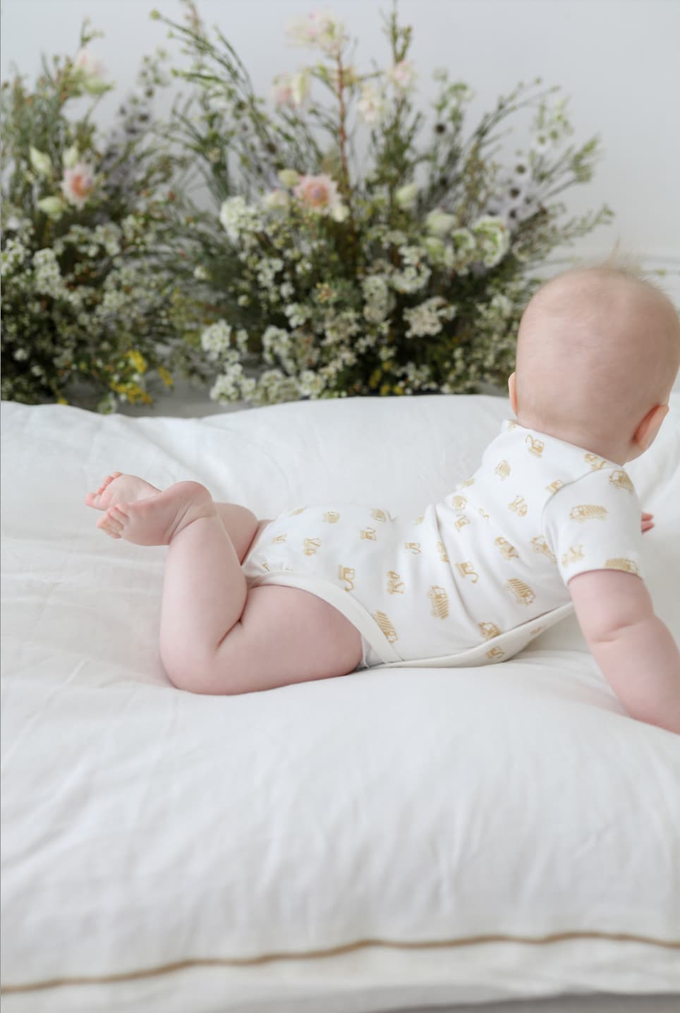Baby lying on a white surface wearing a Truck Kimonos in Mustard Truck