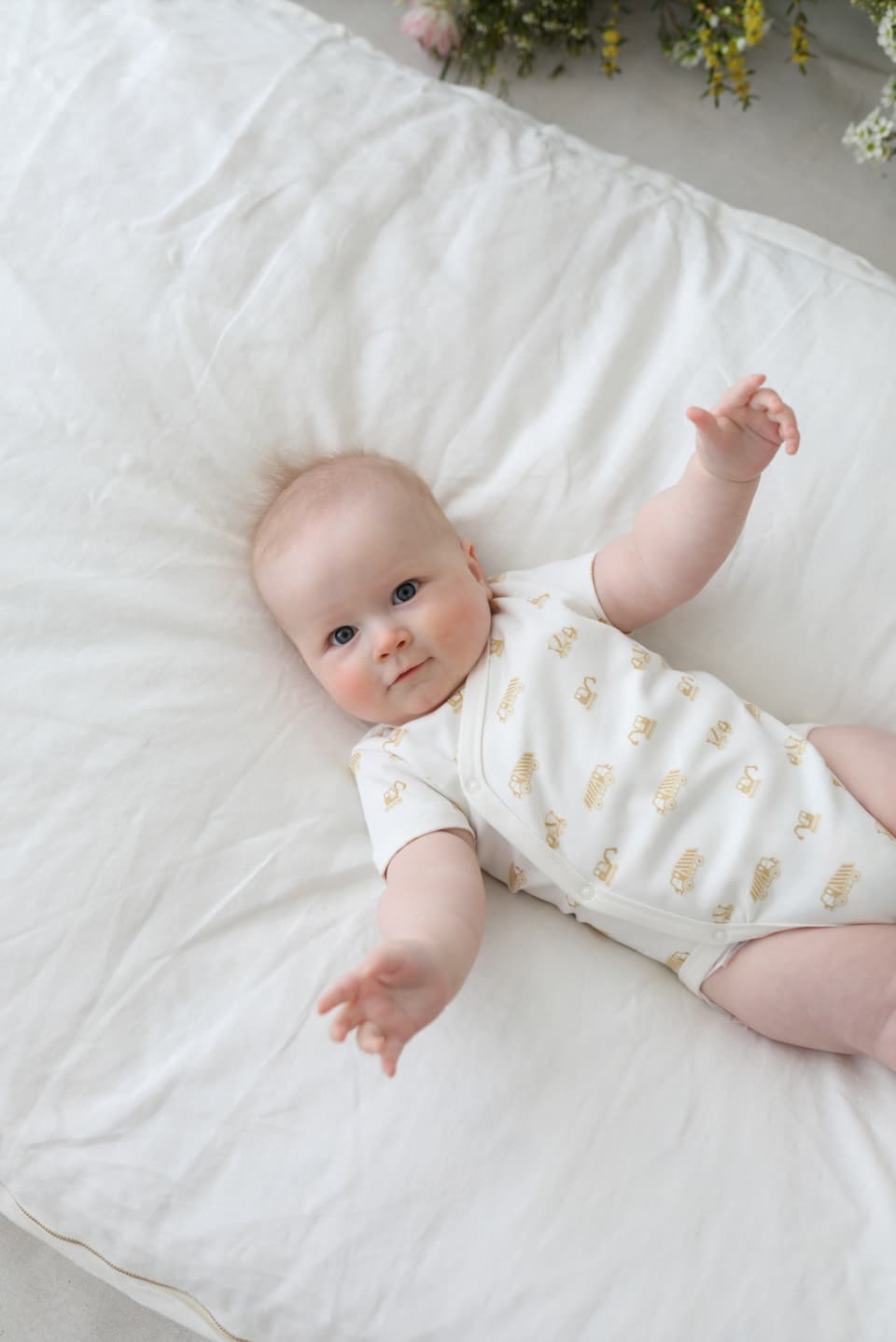 Baby lying on a white mattress wearing a Truck Kimonos in Mustard Truck 
