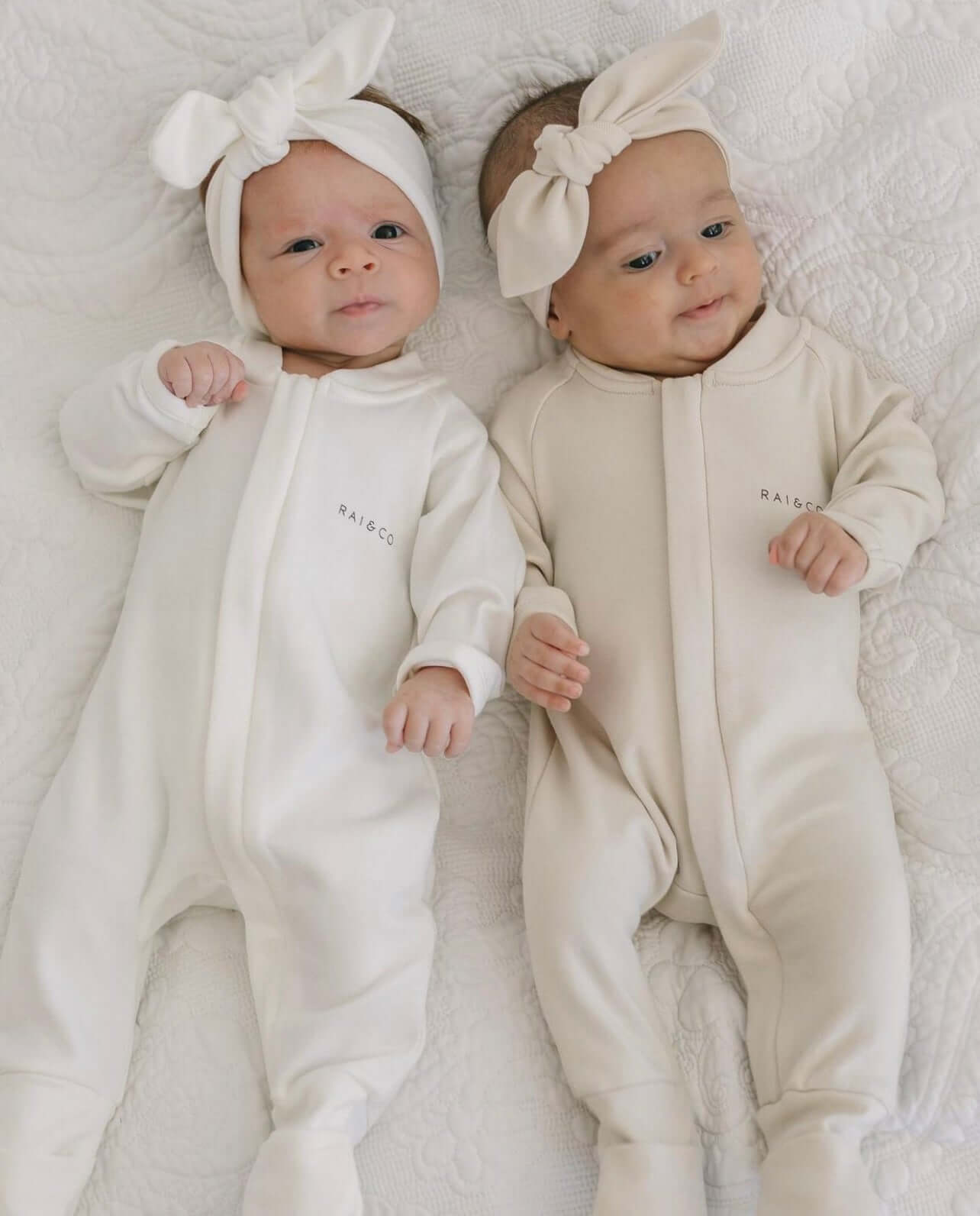 two babies wearing a Apple Headbands in White and Beige on a white bed