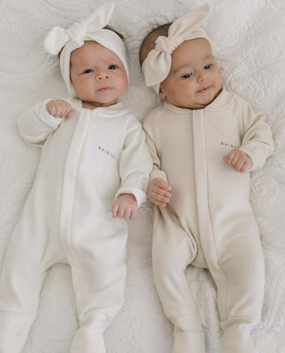 two babies wearing a Apple Headbands in White and Beige on a white bed
