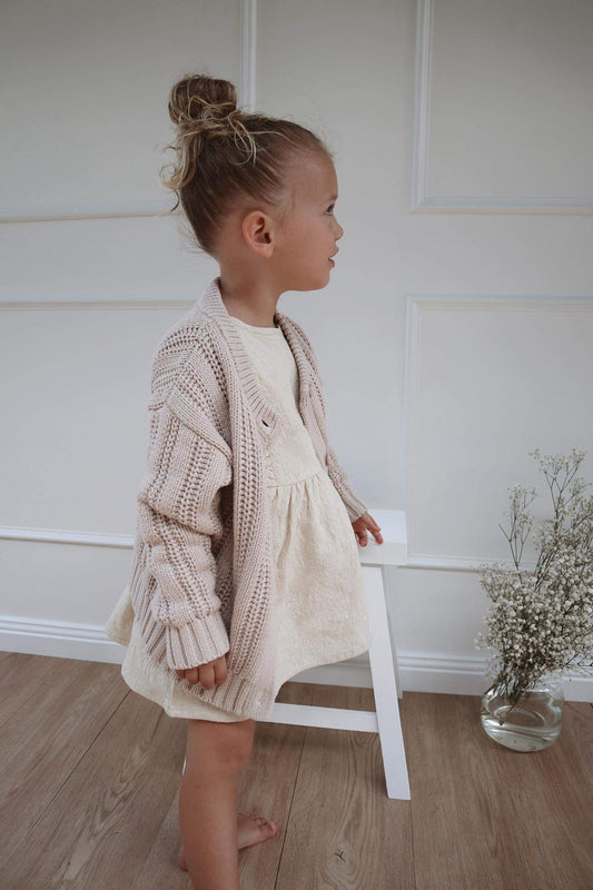 A young child wearing a Chunky Knitted Cardigan in Beige 