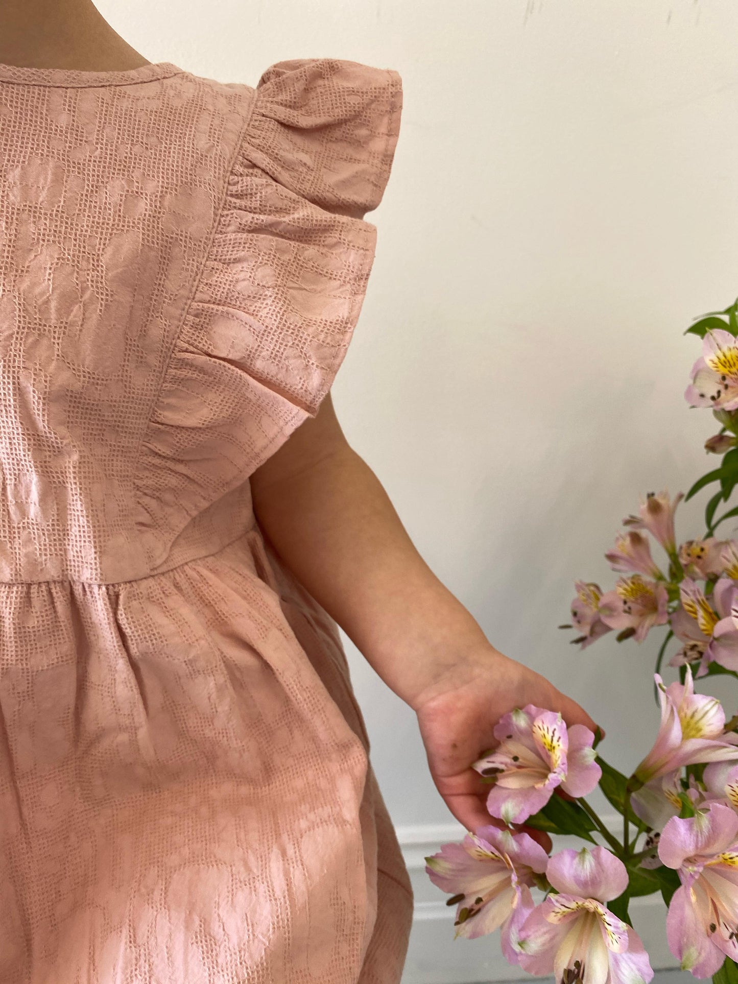 A young child wearing a Lou Lou Frilled Dress With Pilchers in Pink 