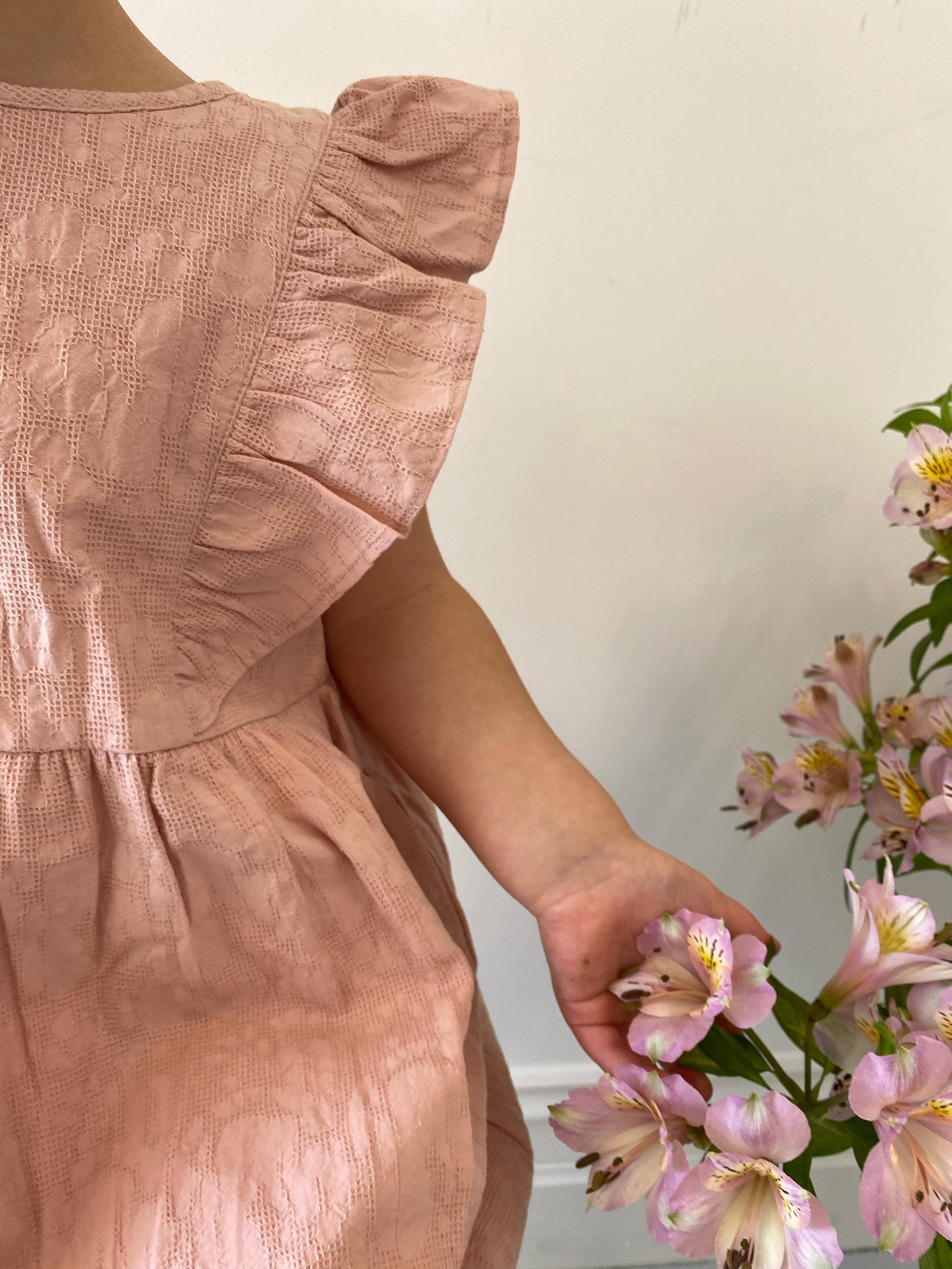 A young child wearing a Lou Lou Frilled Dress With Pilchers in Pink 