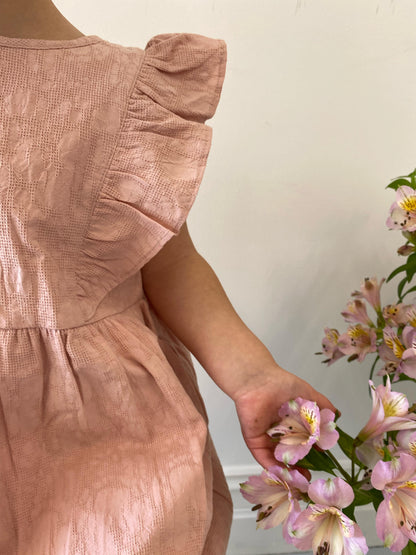 A young child wearing a Lou Lou Frilled Dress With Pilchers in Pink 