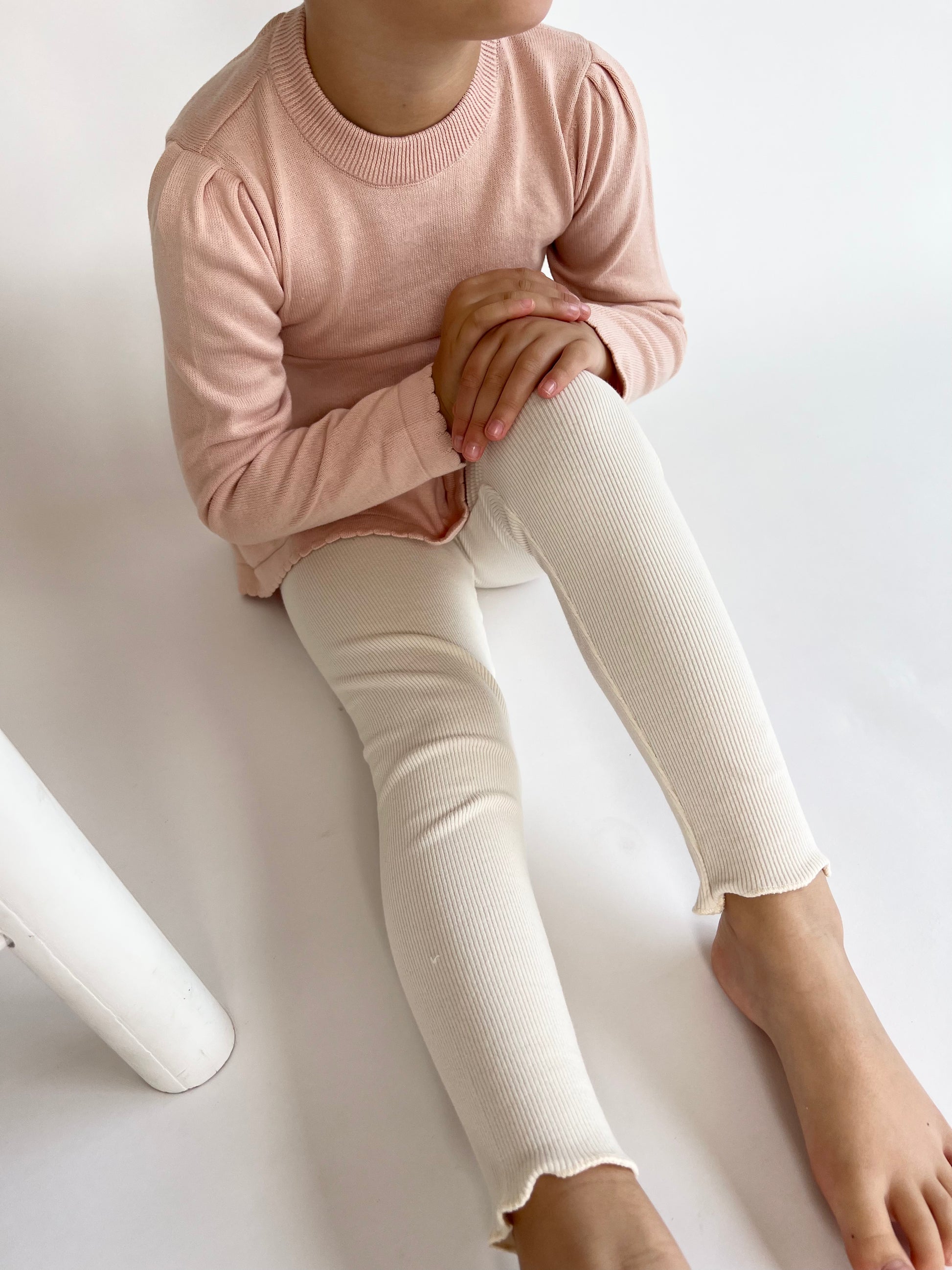 a child wearing a Mini Ribbed leggings in Ivory on a white background