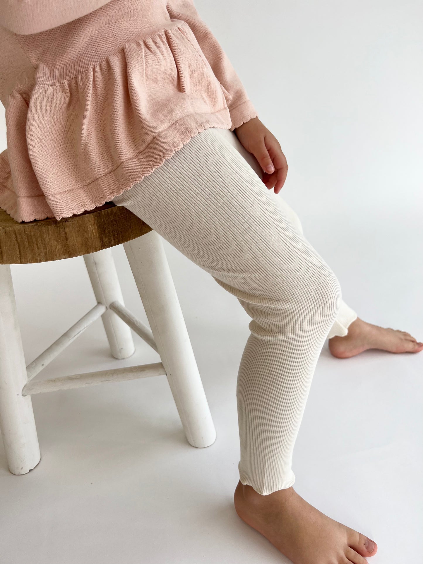 a child wearing a Mini Ribbed leggings in Ivory on a white background