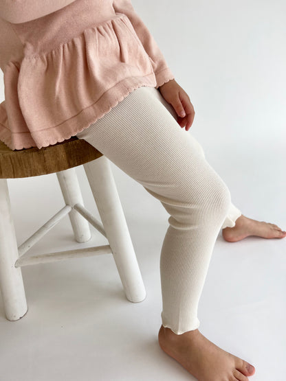 a child wearing a Mini Ribbed leggings in Ivory on a white background